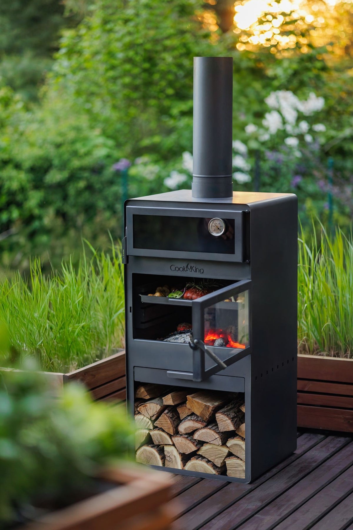 Cook King – Pack VENTO – Brasero cheminée avec four, grille de cuisson et range-bûches — mise en situation